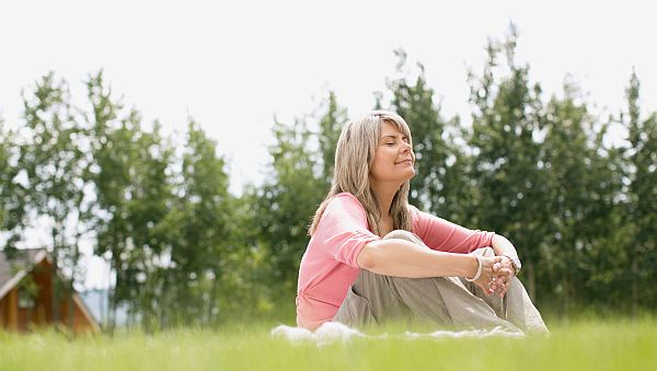 Frau sitzt im Gras und Meditiert
