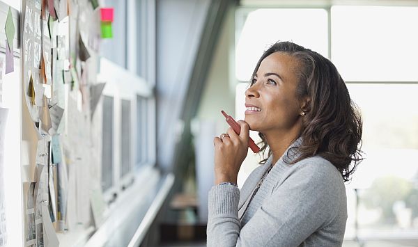 Frau vor Moodboard überlegt, sucht Idee
